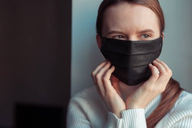 Genç kız kendini virüsün yayılmasından korumak için siyah maske takıyor.