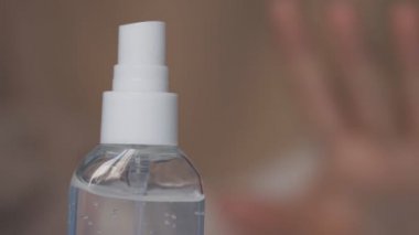 Coronavirus karantinası sırasında evde çalışan bir kadın. Ellerini dezenfektan jeliyle temizliyor. Dezenfektan jelinin görüntülerini kapat.