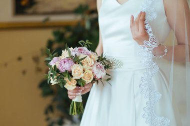 Güzel gelin gül ve Şakayık buket onun elinde tutan bir peçe