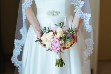 Güzel gelin gül ve Şakayık buket onun elinde tutan bir peçe