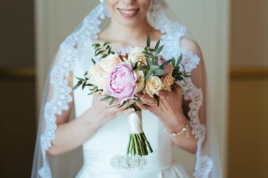 Güzel gelin gül ve Şakayık buket onun elinde tutan bir peçe