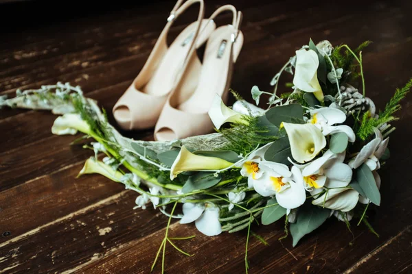Yüksek topuklar ve düğün için Ayrıntılar hazırlanıyor orkide vintage bir ahşap zemin üzerinde bir buket ile ayakkabı