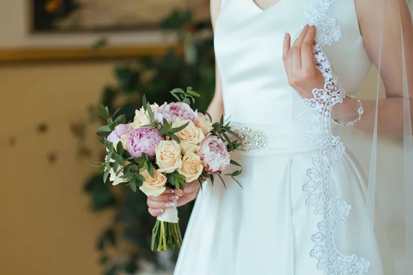 Güzel gelin gül ve Şakayık buket onun elinde tutan bir peçe