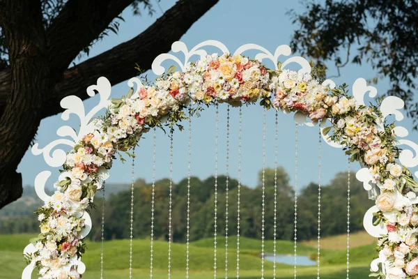 Detalhes de belo arco de casamento de flores em um campo verde de fundo com árvores — Fotografia de Stock