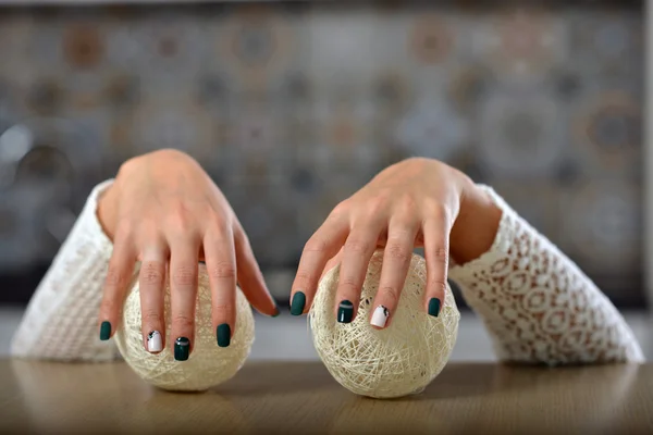 Mãos femininas com manicure segurando as mãos bolas de malha . — Fotografia de Stock