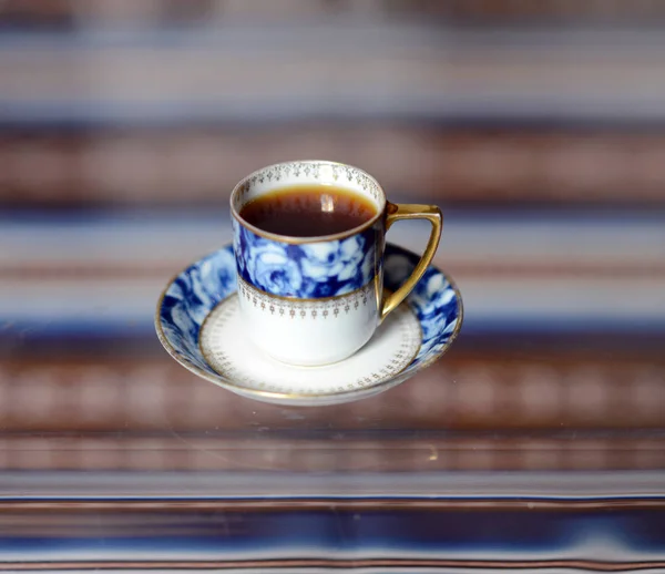Чашка с вкусным ароматным кофе стоит на стеклянном столе . — стоковое фото