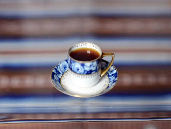 Una tazza con un delizioso caffè profumato costa su un tavolo di vetro . — Foto Stock