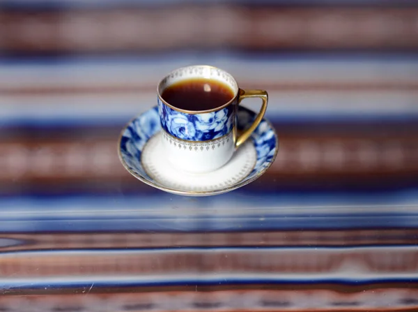 Una tazza con un delizioso caffè profumato costa su un tavolo di vetro . — Foto Stock