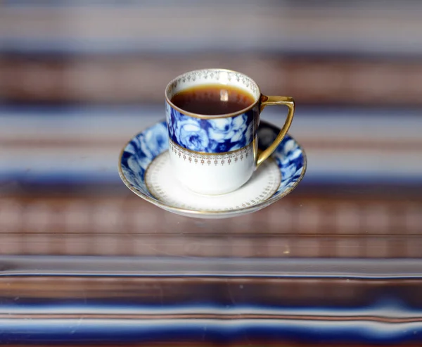 Una tazza con un delizioso caffè profumato costa su un tavolo di vetro . — Foto Stock