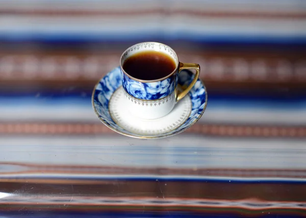 Чашка с вкусным ароматным кофе стоит на стеклянном столе . — стоковое фото