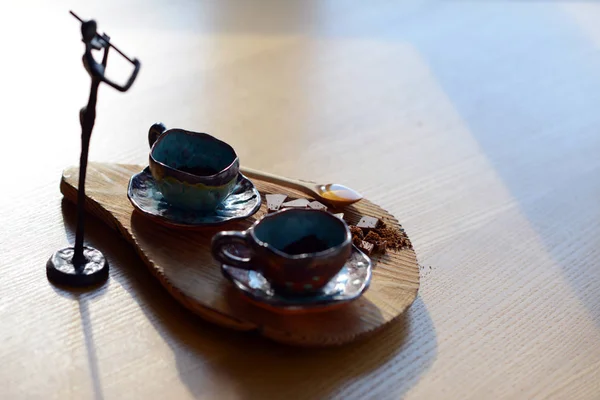 Figurka skrzypek, stojący obok drewniany stojak na które podstawka na filiżankę kawy i czekolady. — Zdjęcie stockowe