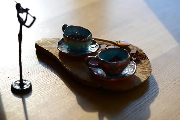 Violinist figurine standing next to a wooden stand on which stand a cup of coffee and chocolate. — Stock Photo, Image