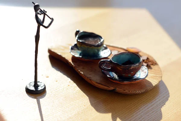 コーヒーとチョコレートのカップをスタンドに木製のスタンドの横に立っているバイオリニストの置物. — ストック写真