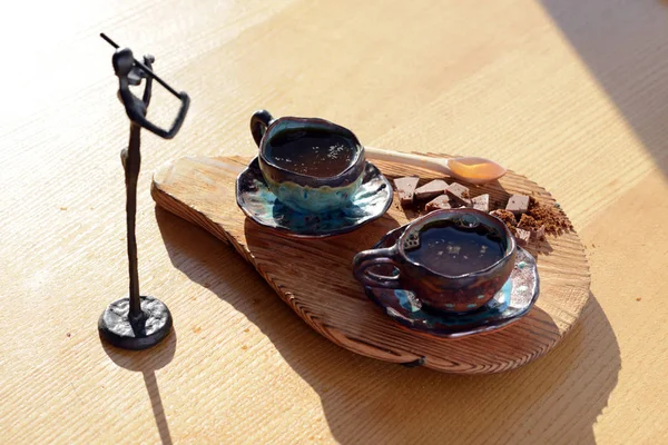 Figura violinista de pie junto a un soporte de madera en el que se encuentra una taza de café y chocolate . —  Fotos de Stock