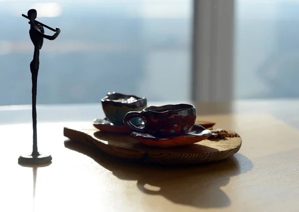 コーヒーとチョコレートのカップをスタンドに木製のスタンドの横に立っているバイオリニストの置物. — ストック写真