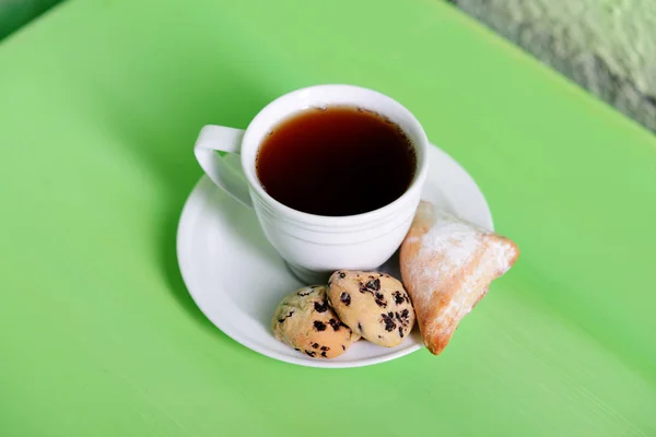 白一杯のお茶。受け皿はクッキーです。乾燥した葉、りんごとみかんのカップの横にあります。. — ストック写真