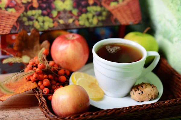 Beyaz bir fincan çay. Fincan beyaz bir daire üzerinde duruyor. Çikolata kurabiye limon parçaları ve bir buket dağ kül Kupası yanındaki vardır.
