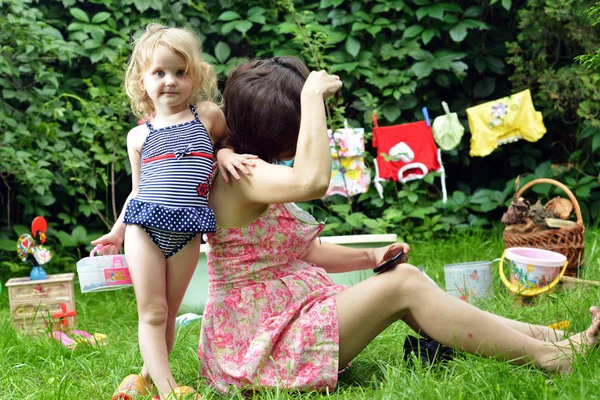 Schwangere Mutter und Tochter spielen auf dem Rasen. — Stockfoto