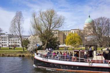 Brandenburg, Potsdam 'daki tarihi binanın manzarası. Ön planda, Havel nehri Dostluk Adası 'nın arkasında, güzel bir yeşil park olarak görülür. Nehirde tarihi bir vapur turistlerle birlikte batıyor. Arka tarafta.