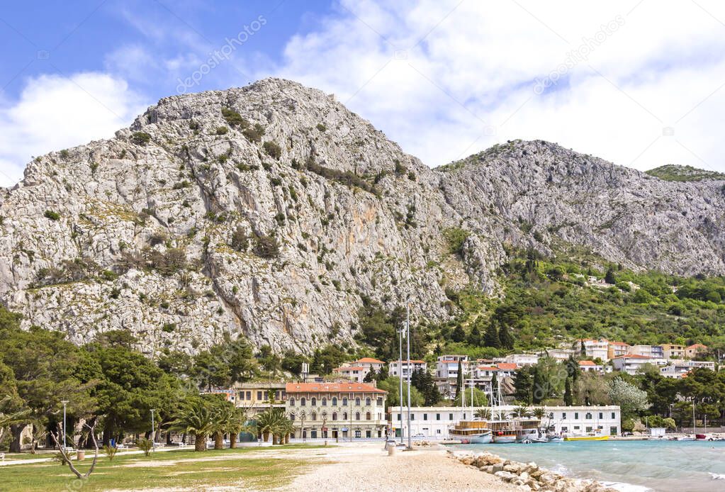 View to the mountain and the town Omis at the Adriatic Sea. In foreground is seen a park and a little harbor with ships. Omis is a town and port in the Dalmatia region of Croatia, and is a municipality in the Split-Dalmatia County