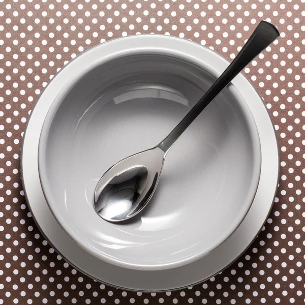 Gray bowl on white plate with spoon — Stock Photo, Image