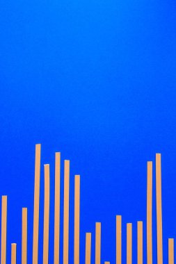 Sarı uzun pişmemiş makarna ile mavi arka plan.