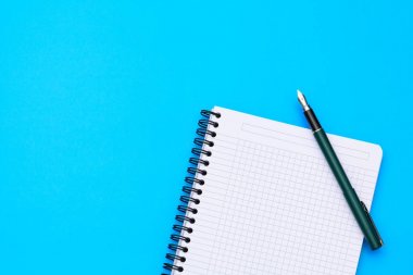 Üstten Görünüm üstünde boş bir defter kalem düz ile mavi arka plan üzerinde yatıyordu.