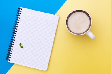Boş defter ve kahve, sarı ve mavi kağıt arka plan üzerinde ayrılmış Üstten Görünüm.