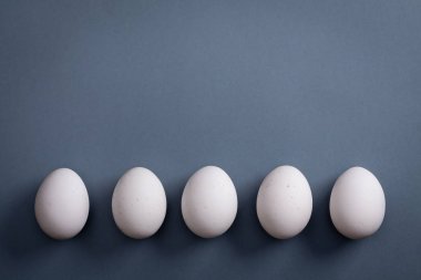 Beyaz yumurta satırında gri kağıt arka plan üzerinde döşeme.