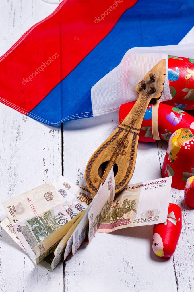 Russian symbols matryoshka, balalaika, rubles cash and flag of russian federation on wooden background.