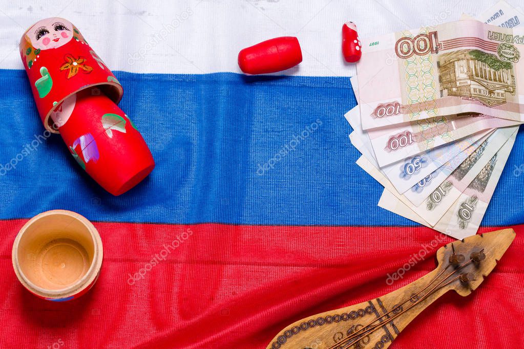Russian symbols matryoshka, balalaika, rubles cash and flag of russian federation on wooden background.