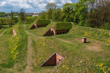 Toprak ve çimlerle kaplı sığınaklar, tepenin altına gizlenmiş tuğlalar ve çelikten sığınaklar..