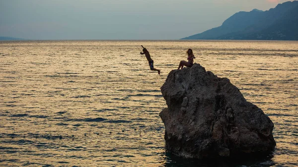 Young people\'s jumping to the water from big stone, Brela, Croatia.