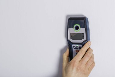 İnsan eli delmeden önce kablo detektörüyle duvarı tarıyor..