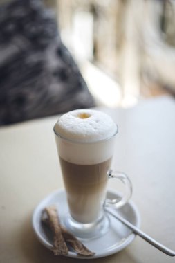 Tahta masada bir bardak sıcak latte ve şeker.