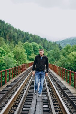 Genç bir adam tren yolunda duruyor..