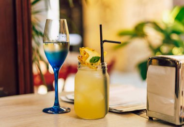 Kafedeki ahşap masada limonlu soğuk yaz içeceği. Yeşil yaprak doğası soyut arkaplan