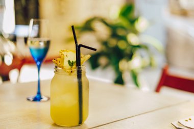 Masada bir bardak beyaz şarap ve sarı kokteyl. Lezzetli ananas kokteyli.