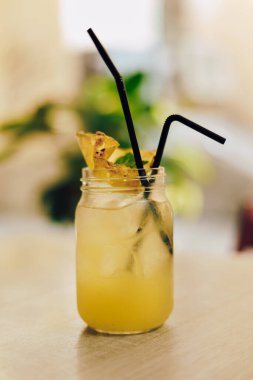 Kafedeki ahşap masada limonlu soğuk yaz içeceği. Yeşil yaprak doğası soyut arkaplan