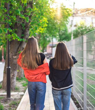 Sırt çantalı iki mutlu kız şehirde dolaşıyor.