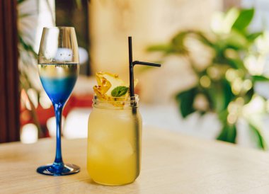 Kafedeki ahşap masada limonlu soğuk yaz içeceği. Yeşil yaprak doğası soyut arkaplan