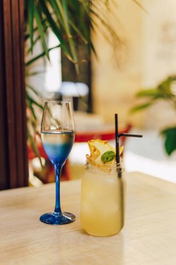 Kafedeki ahşap masada limonlu soğuk yaz içeceği. Yeşil yaprak doğası soyut arkaplan