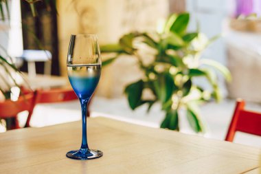 Masada bir bardak beyaz şarap. Mavi cam.