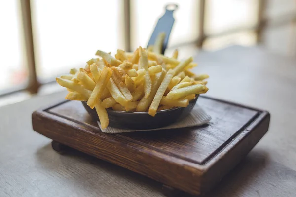 French fries in frying pan on wooden table