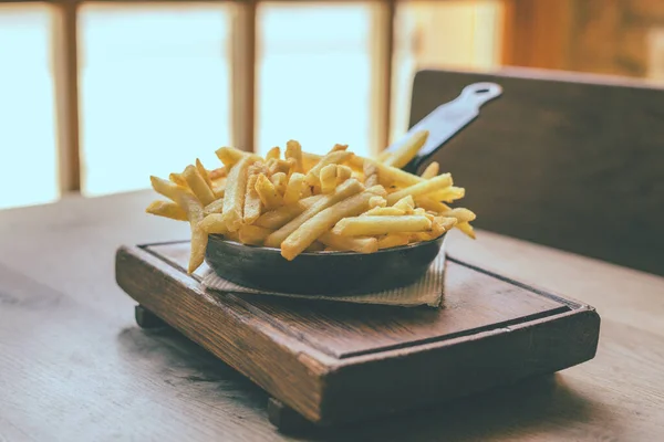 French fries in pan on wooden table