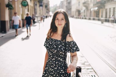 Güzel, gülümseyen bir kadın kalabalık bir şehirde yürüyor.