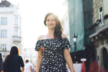 Kalabalık şehir caddesinde yürüyen güzel, gülümseyen bir kadın.