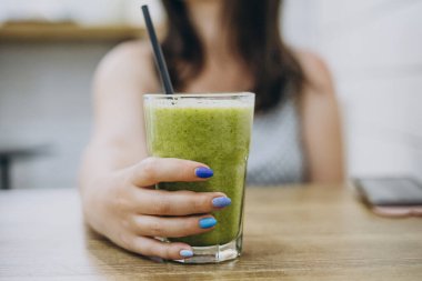 Manikürlü kadın eli yeşil smoothie tutuyor. Ispanak püresi.