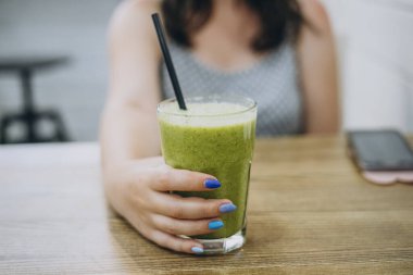 Manikürlü kadın eli yeşil smoothie tutuyor. Ispanak püresi.