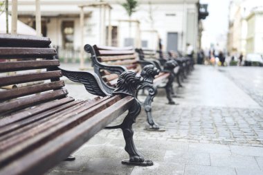 Şehir merkezindeki ahşap banklar. Şehirde rahat kahverengi banklar var. Yazın güneşli bir günde eski kasabada ahşap banklar.